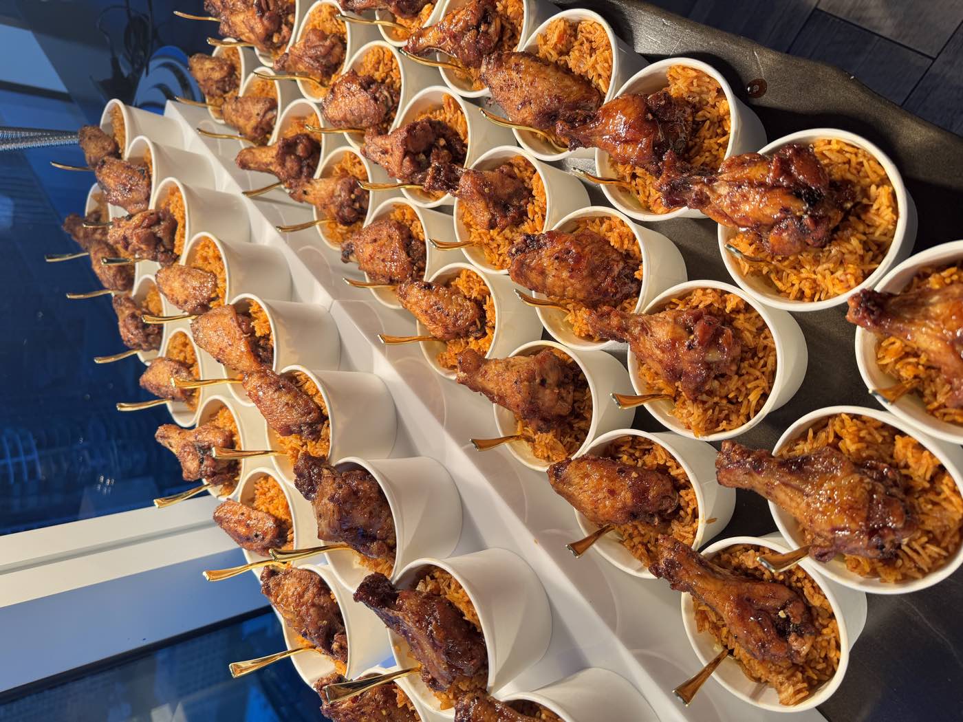 Individual jollof rice and jerk chicken cups by GourmetMaria, styled for a corporate event